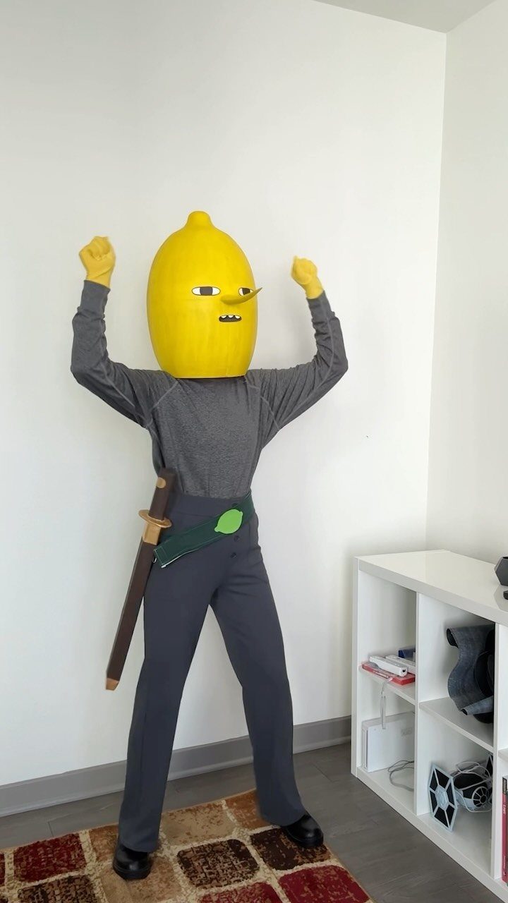 Person in a DIY lemon head costume with a sword posing indoors.