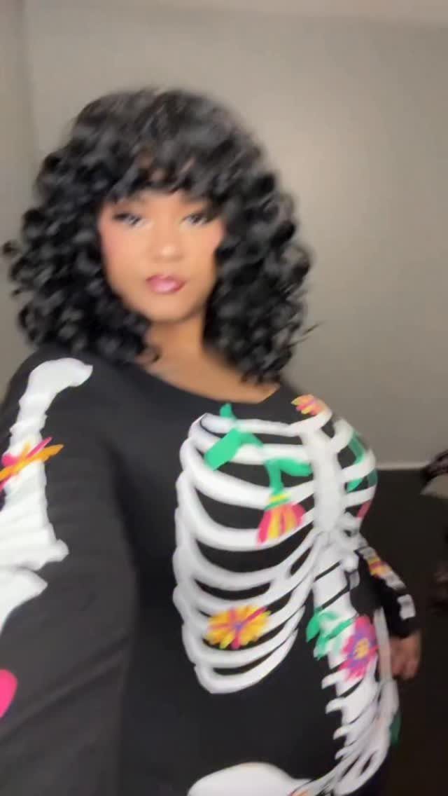 Plus-size woman wearing a black skeleton costume shirt with colorful floral accents.