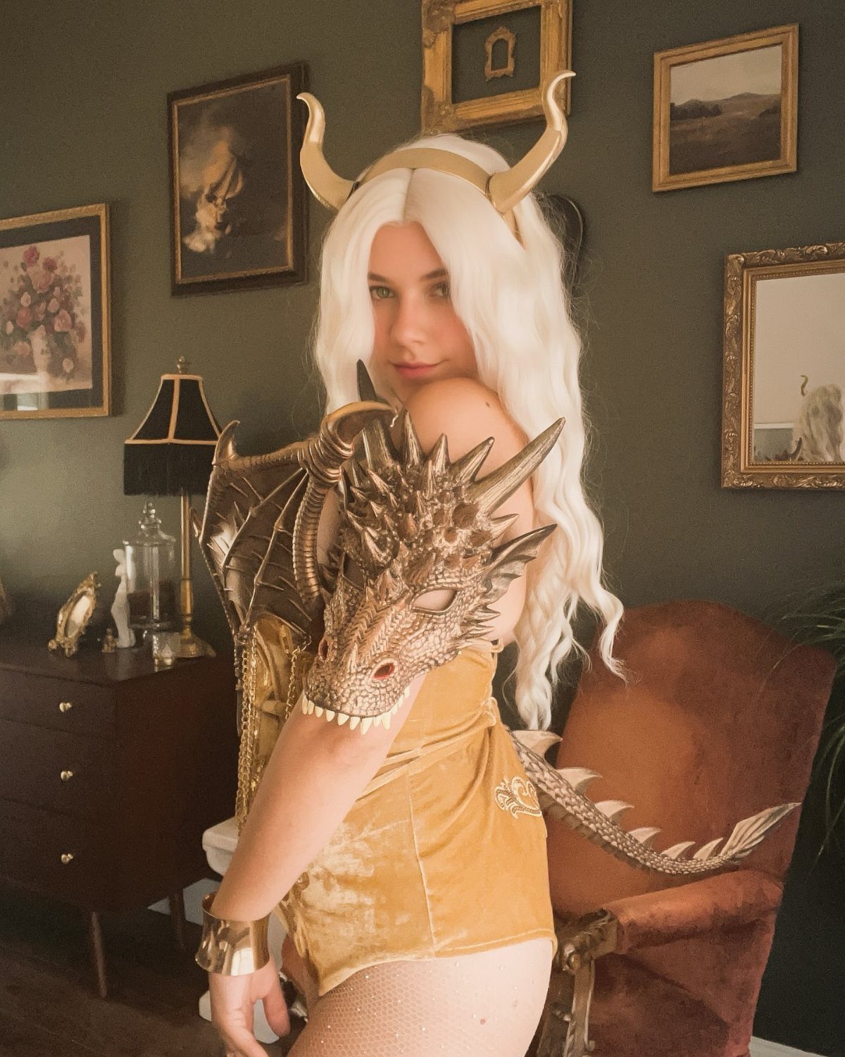 Woman in gold dragon warrior costume with white hair and dragon shoulder armor.
