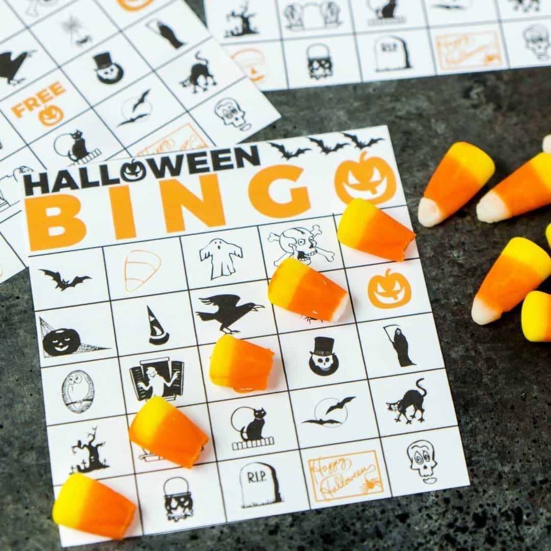 Halloween bingo cards with candy corn pieces used as markers on a dark surface