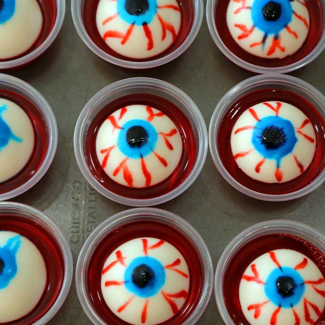 Edible eyeballs in red liquid served in small clear plastic cups.