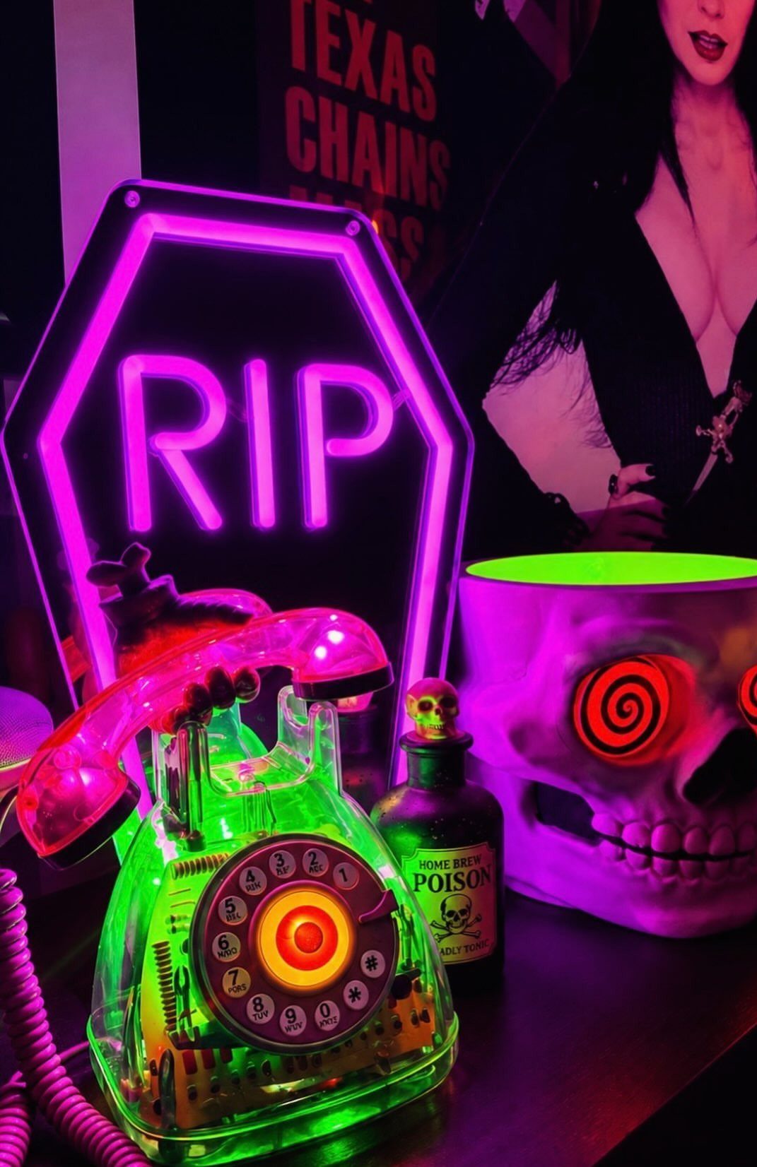 Glowing green rotary phone next to a purple RIP neon sign and skull bowl.
