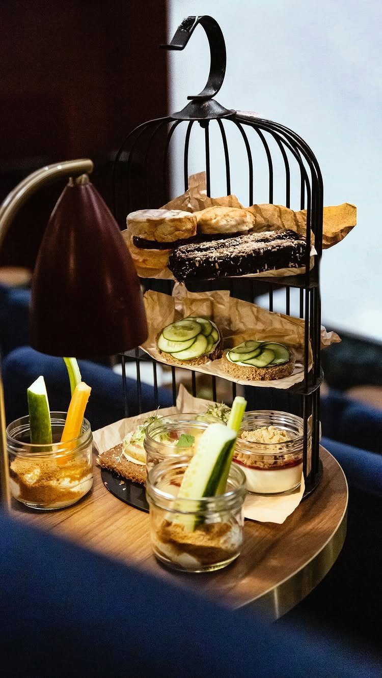 Birdcage tiered stand with cucumber sandwiches, scones, and vegetable dip appetizers.