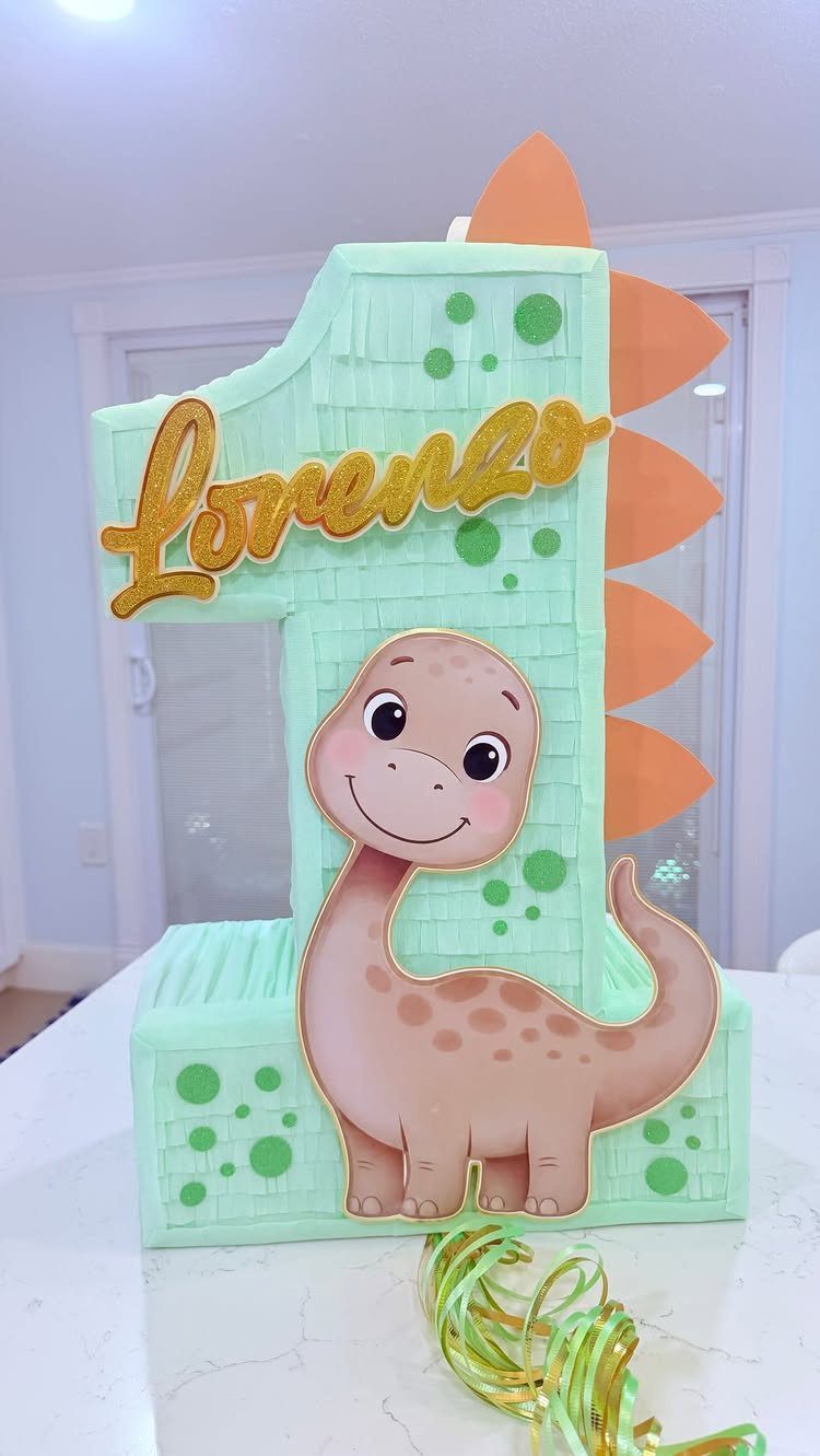 Dinosaur themed number one piñata with gold lettering and orange spikes.