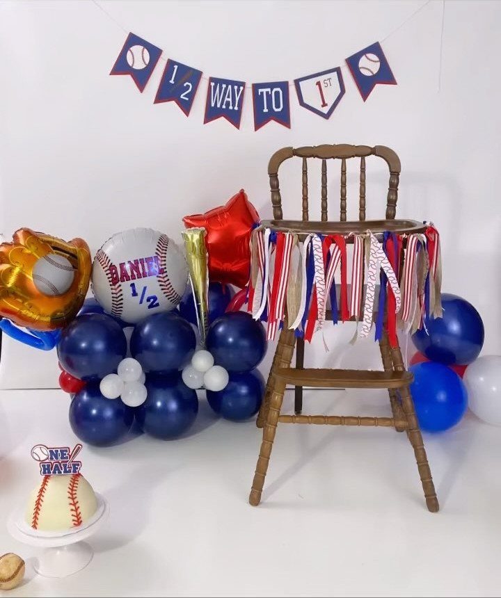 Wooden highchair with a red, white, and blue baseball banner and balloons.