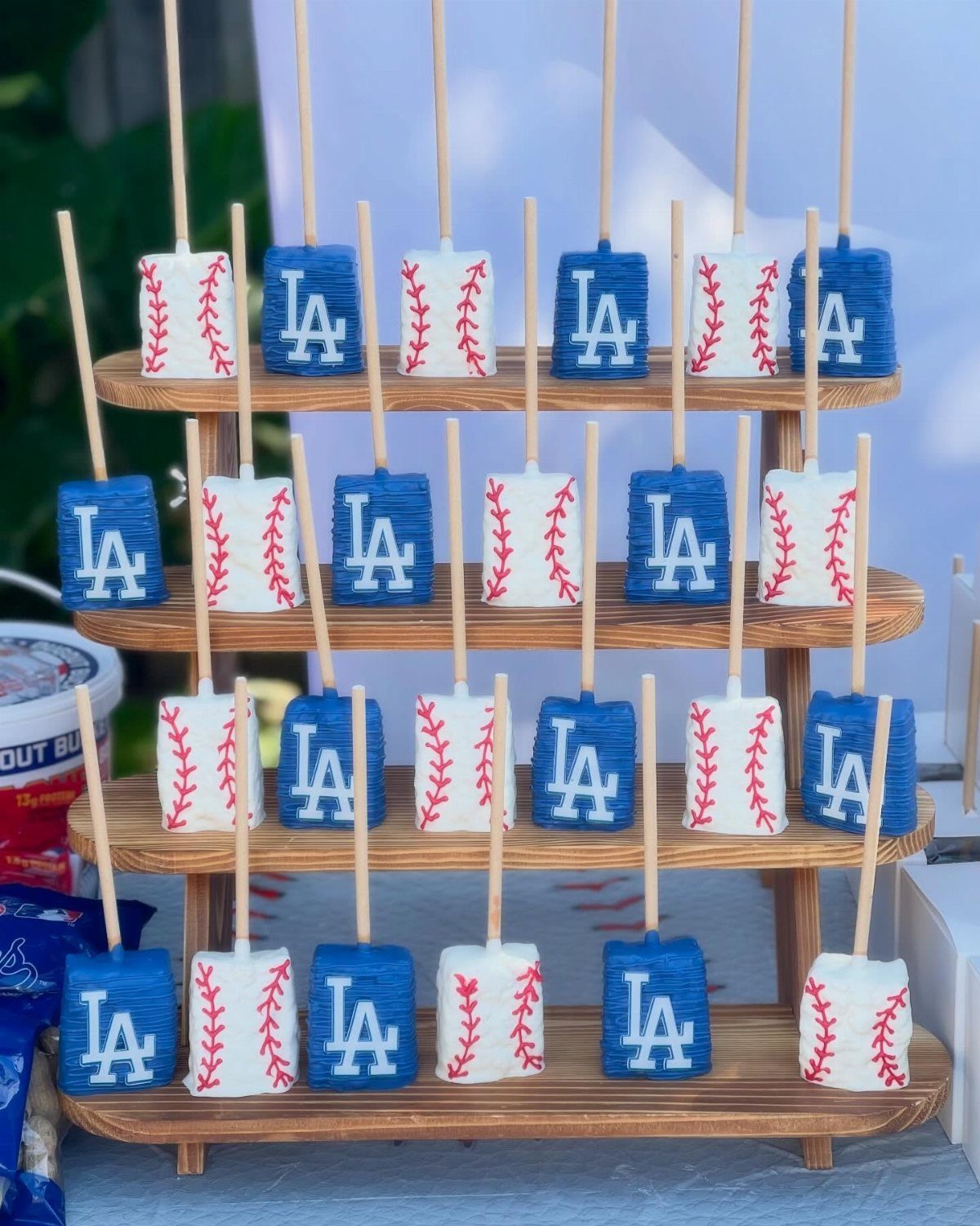 Baseball and LA jersey themed marshmallow pops on a wooden tiered display stand.