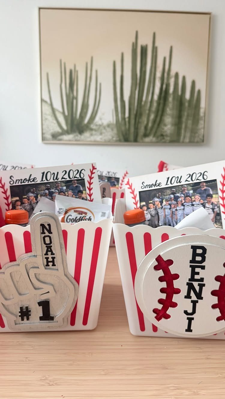Personalized baseball party favor boxes with foam fingers and baseball cutouts on wood.