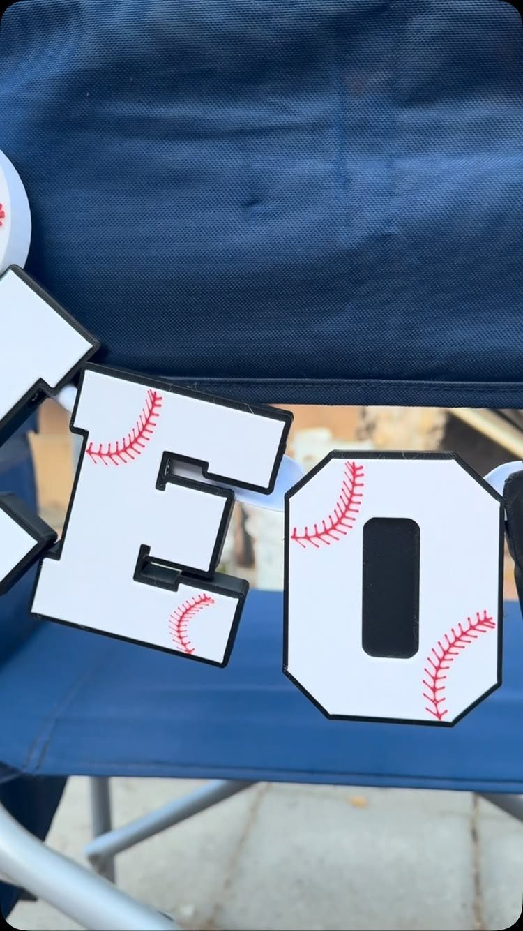 Baseball themed cutout letters spelling LEO resting on a blue folding chair