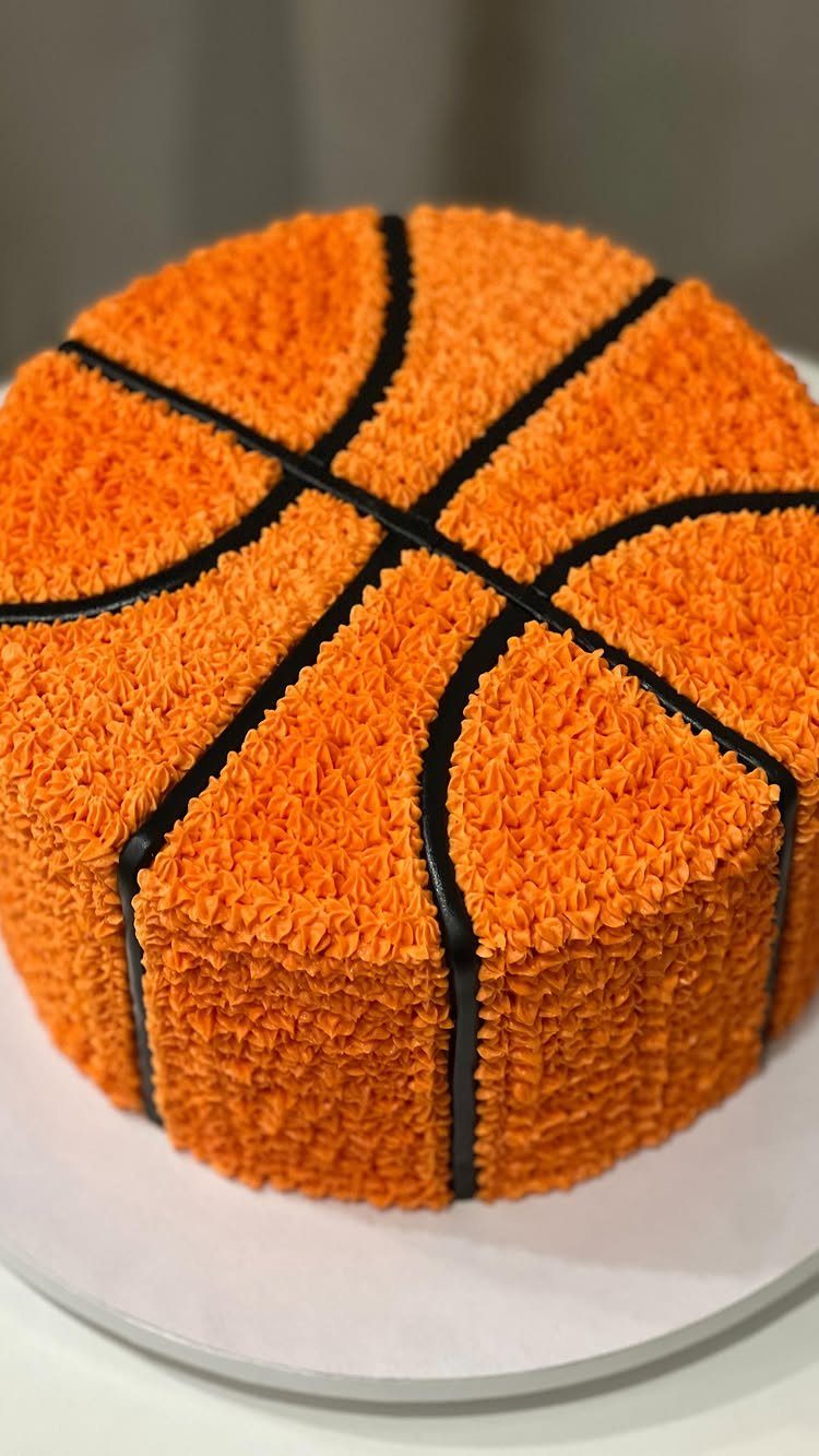 Basketball cake with orange textured frosting and black icing lines on white board