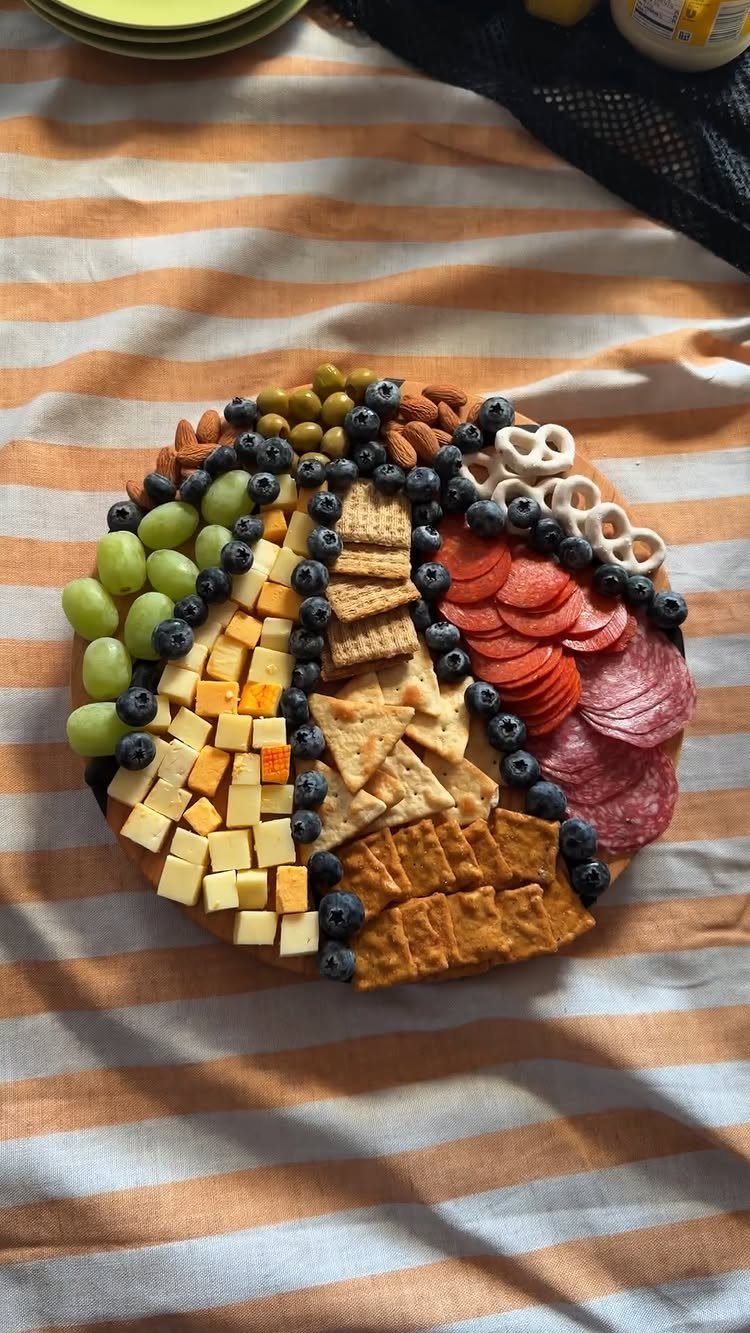 Basketball-shaped charcuterie board with cheese, fruit, and meats on striped tablecloth