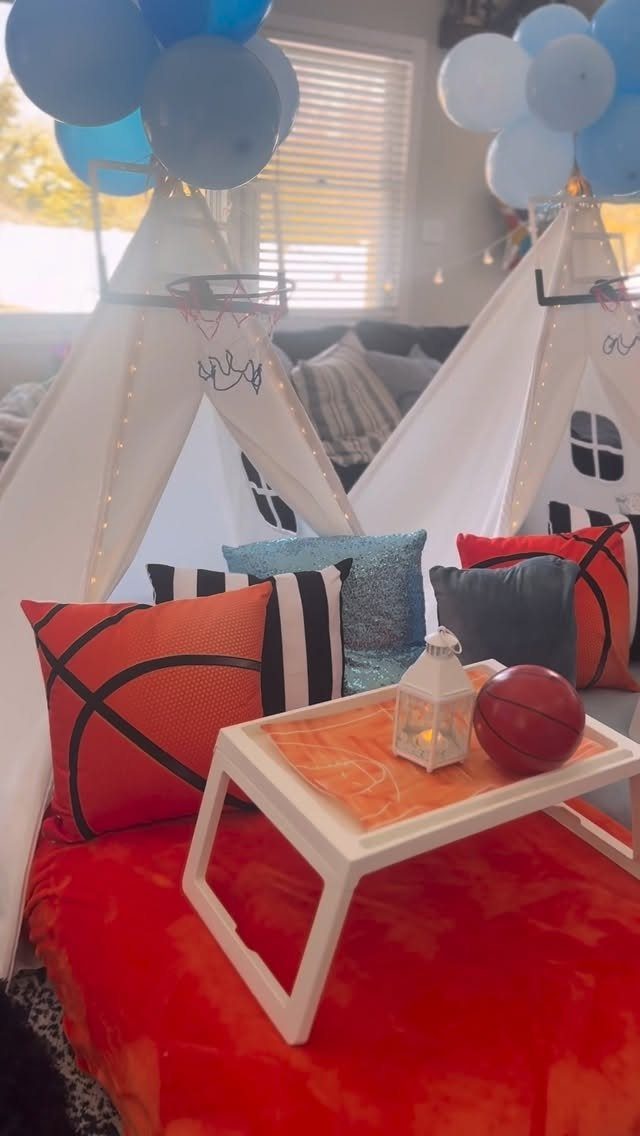 Basketball themed party setup with teepees, blue balloons, and basketball patterned pillows.