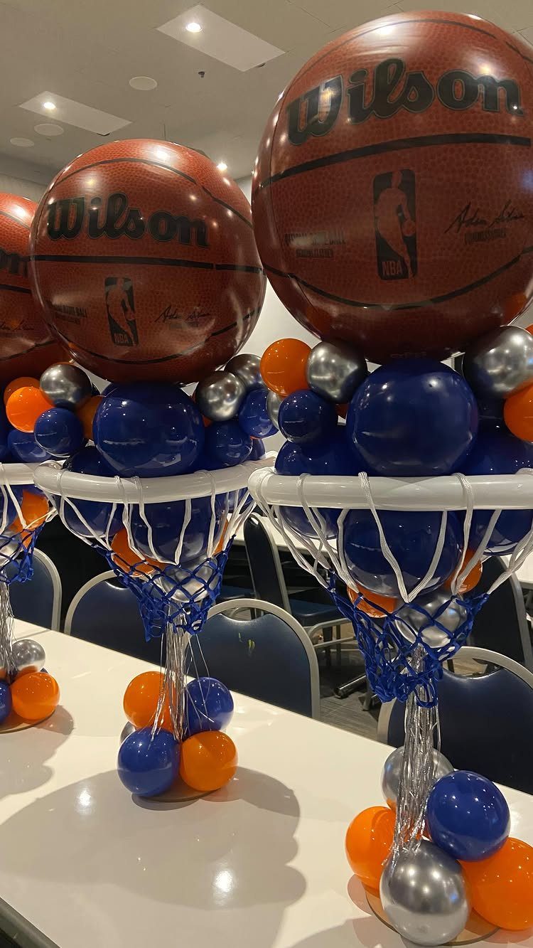 Basketball-shaped balloons and blue, orange, and silver balloons in mini basketball hoops.