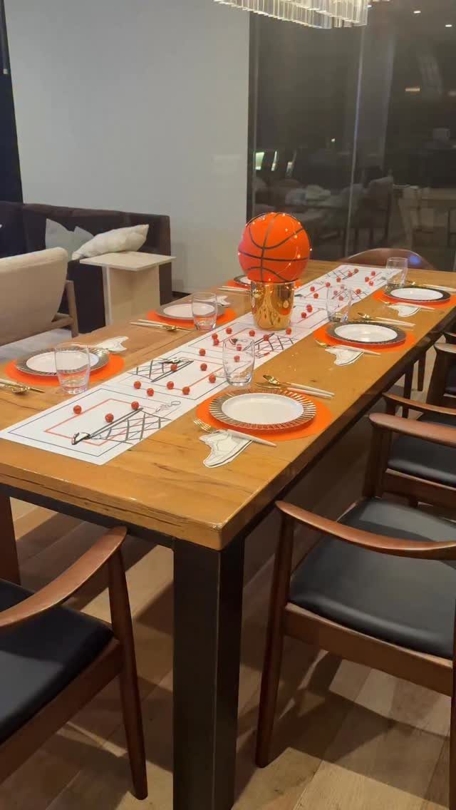 Basketball-themed table setting with orange placemats and a basketball centerpiece on a wooden table