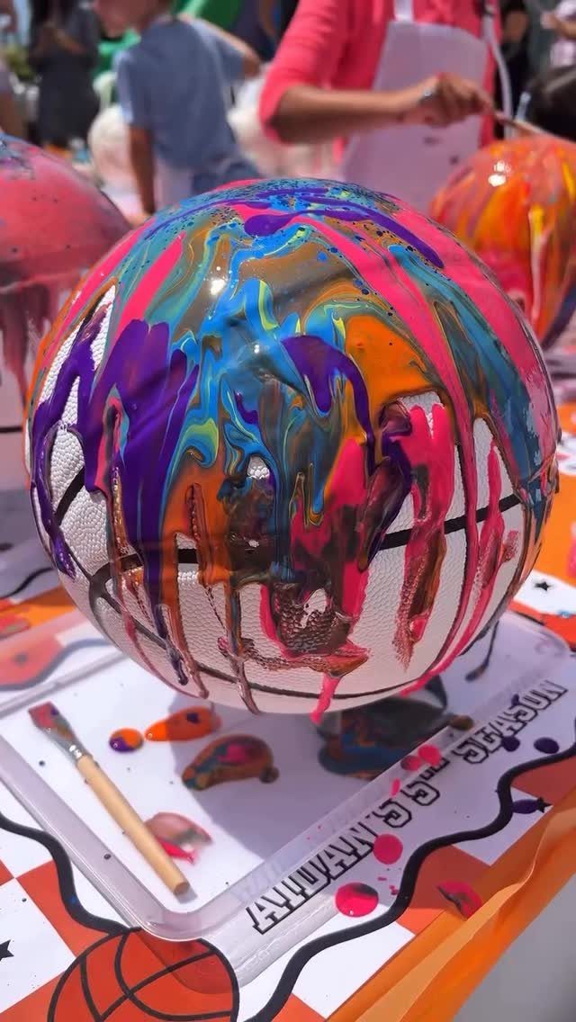 White basketball covered in colorful dripping paint on a themed party table