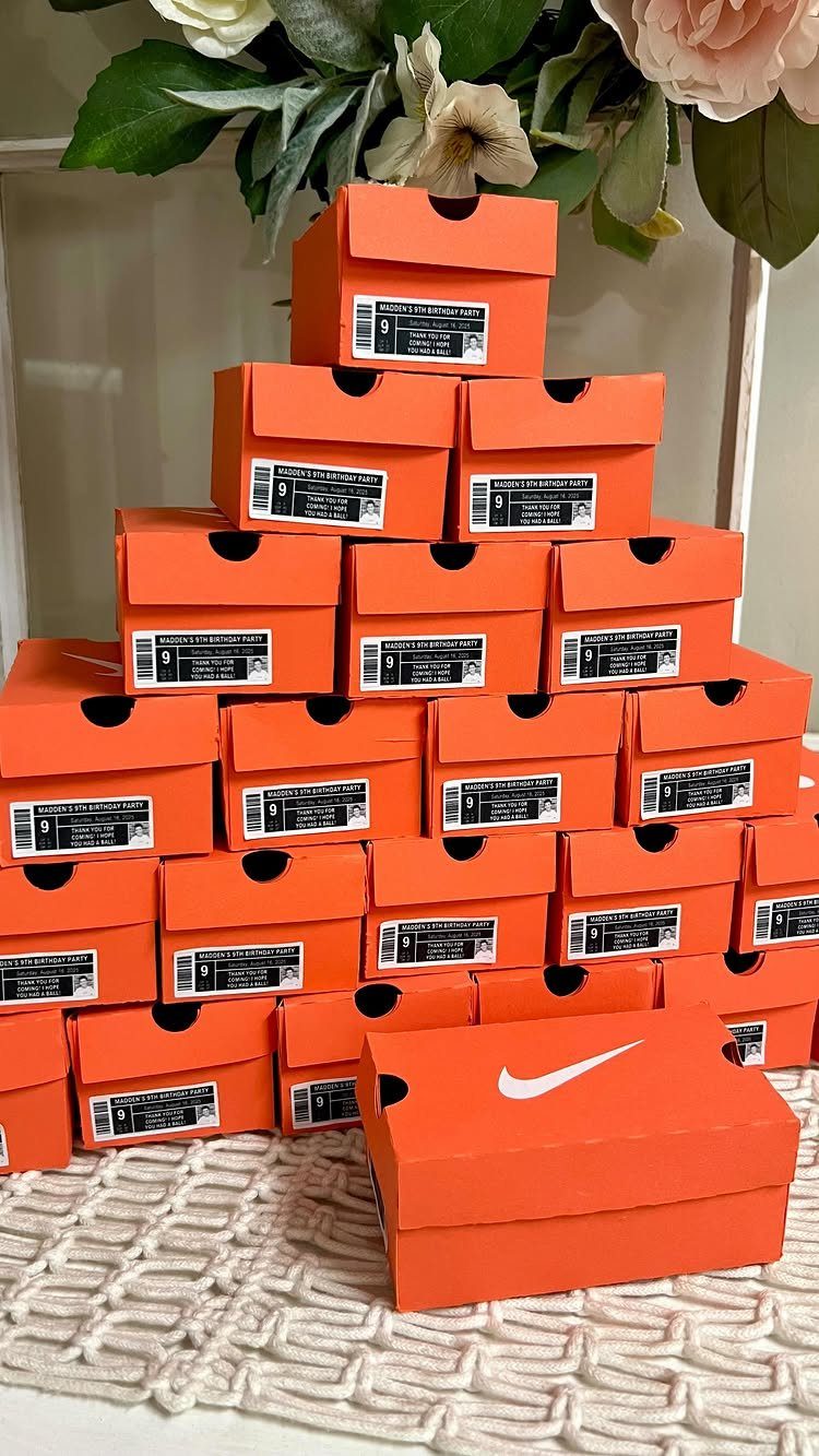 Orange Nike shoe boxes stacked in a pyramid on a white textured surface.