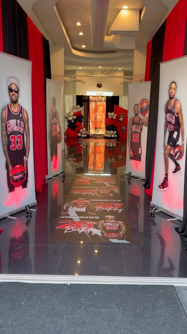 Basketball themed event decor with player banners, red curtains, and printed floor graphics.