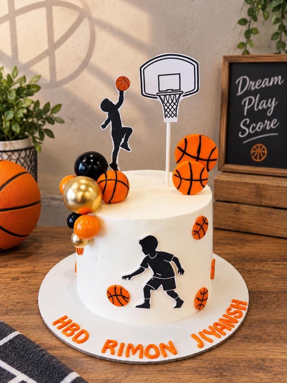 White basketball cake with a hoop topper, orange basketball decorations, and player silhouettes.
