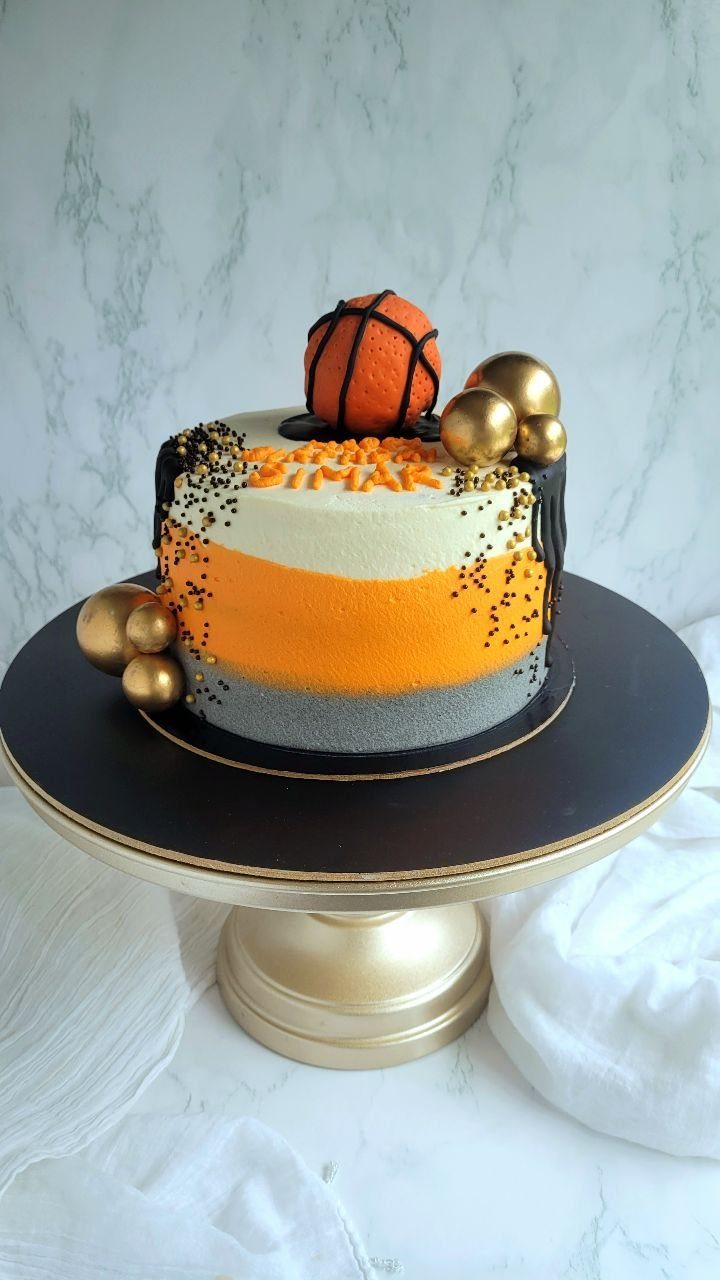 Round striped cake with a small basketball topper on a gold stand.