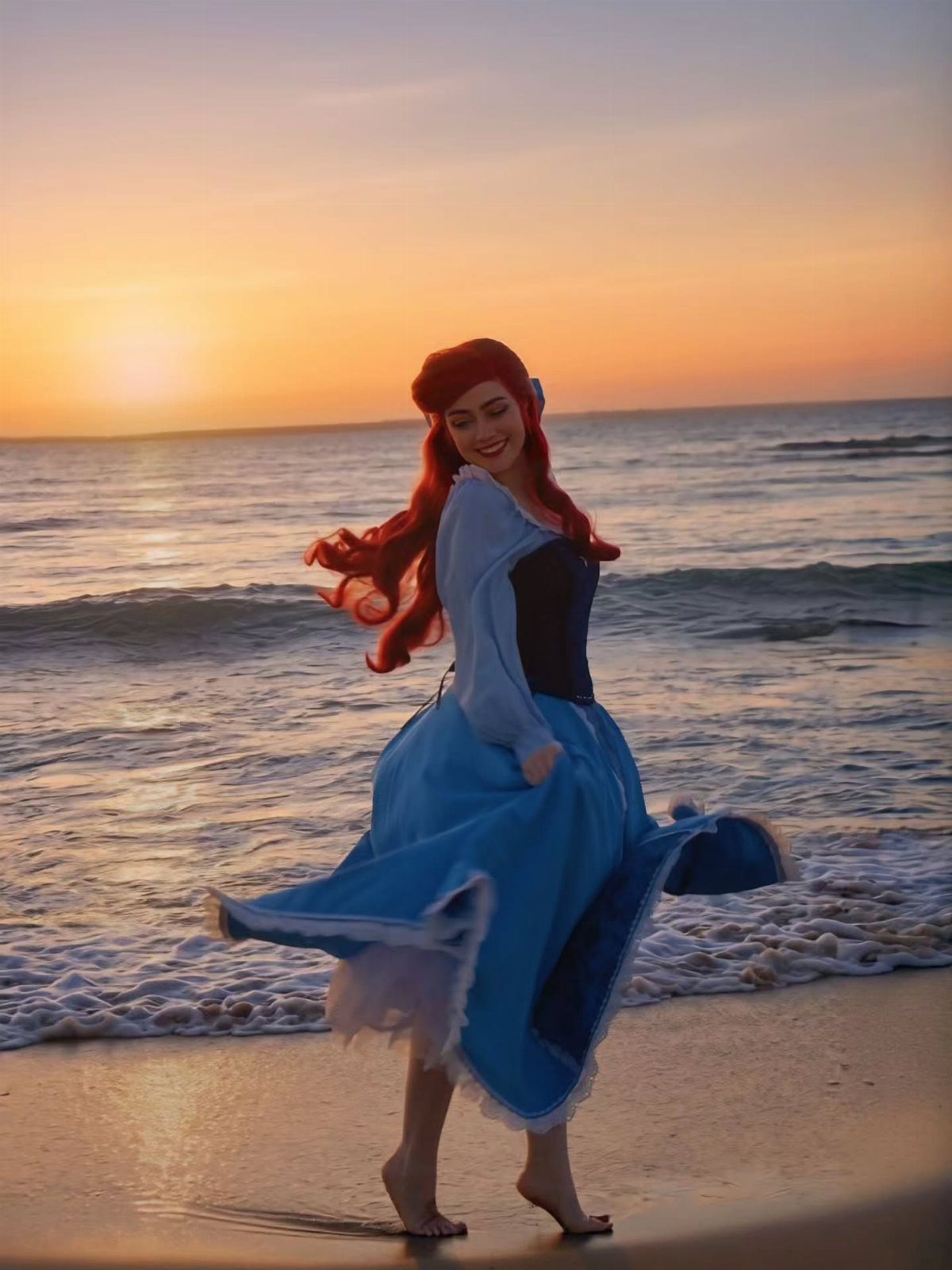 Woman in a blue Ariel costume posing on a beach during a sunset.
