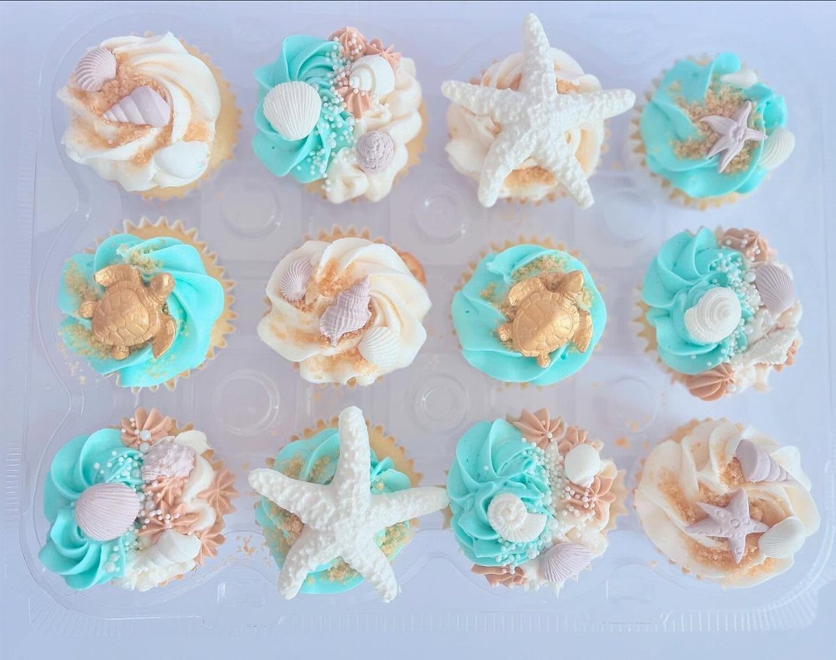 Beach themed cupcakes with blue frosting, edible seashells, starfish, and gold crabs.