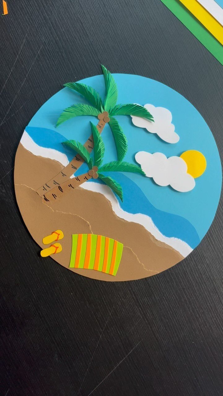 Circular paper craft of a beach scene with palm trees, sun, and towel.
