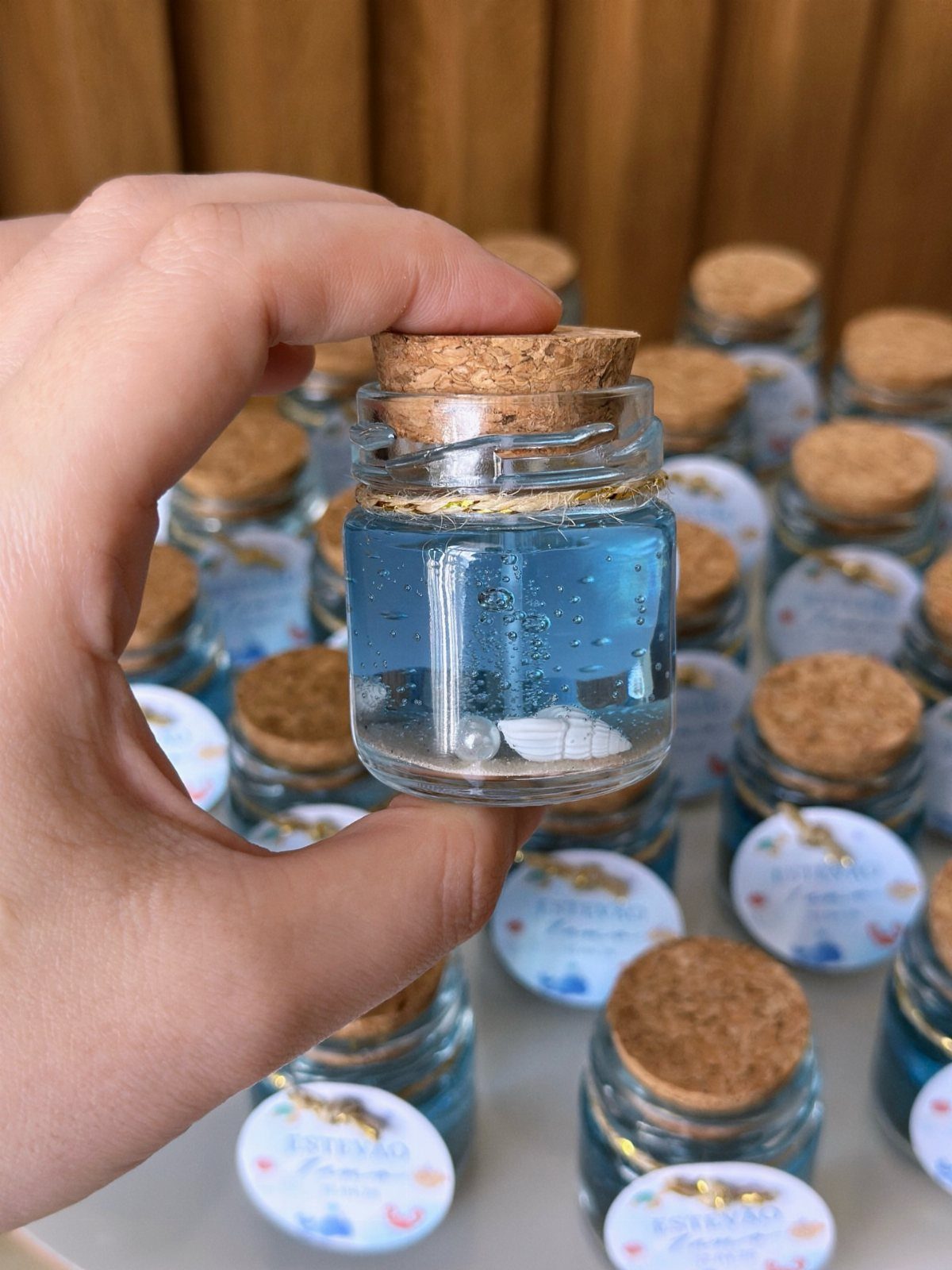 Small glass jars filled with blue liquid and seashells as party favors.