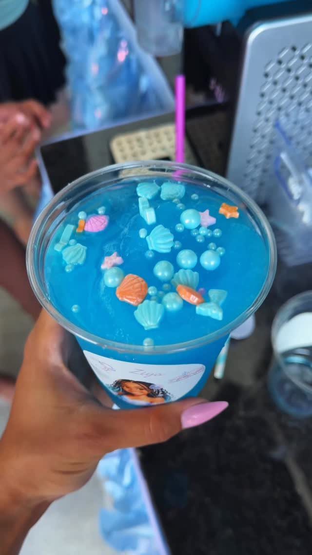 Blue frozen drink topped with seashell and starfish candies in a plastic cup