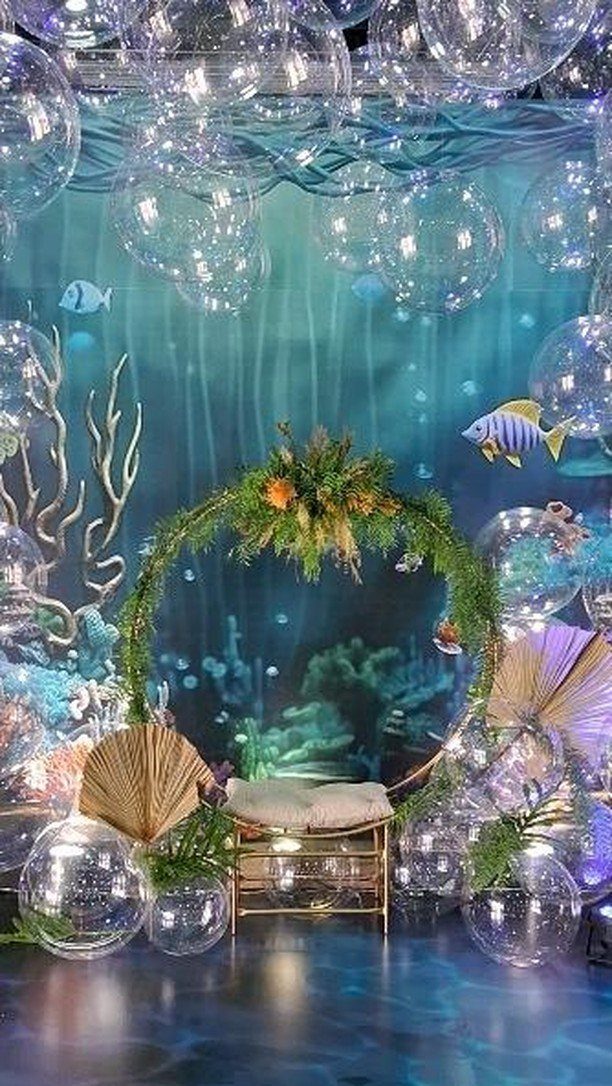 Underwater themed party setup with blue backdrop, floral arch, and clear bubbles.