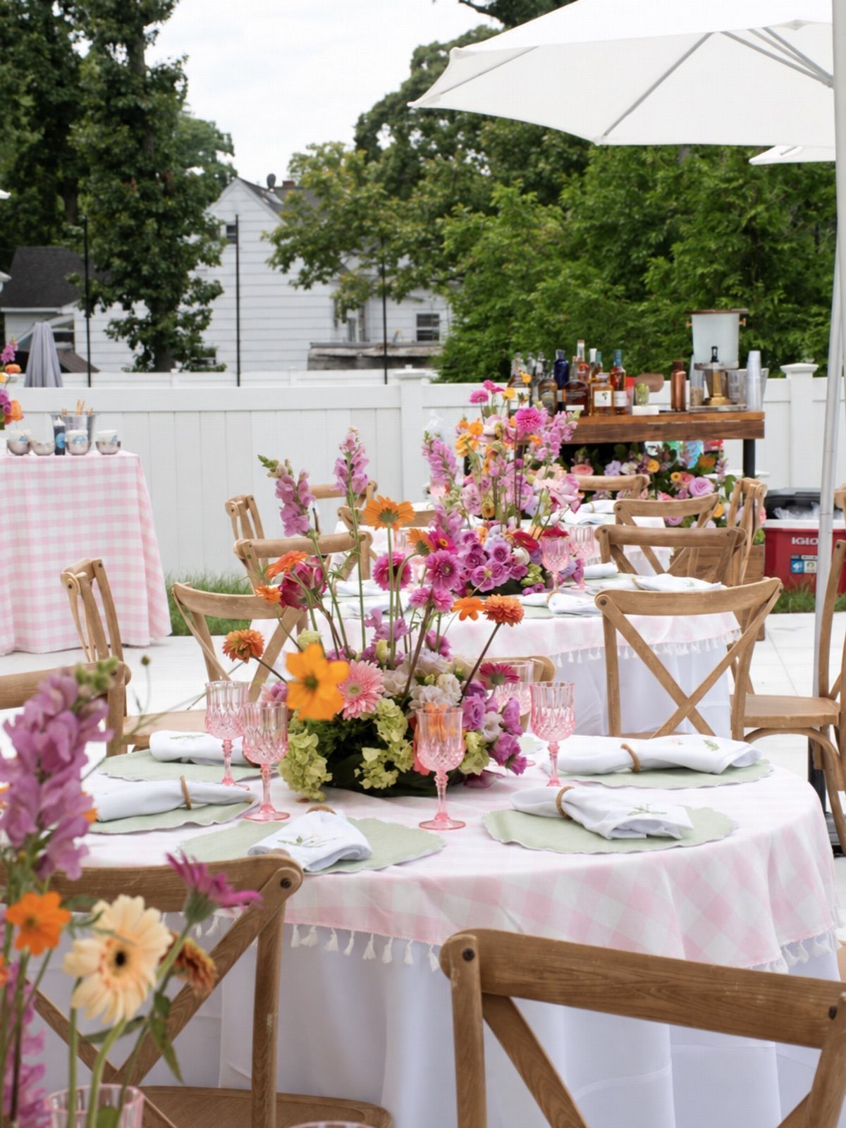 Round table with pink checkered cloth and colorful floral centerpiece in outdoor setting