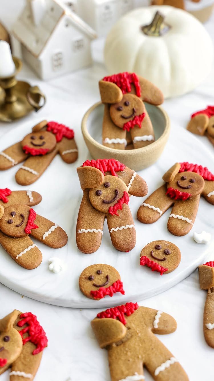Decorated gingerbread man cookies with red icing on a white marble surface.