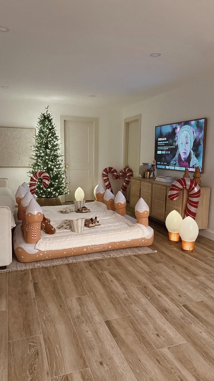 Gingerbread house floor mattress in a living room with a Christmas tree and TV.
