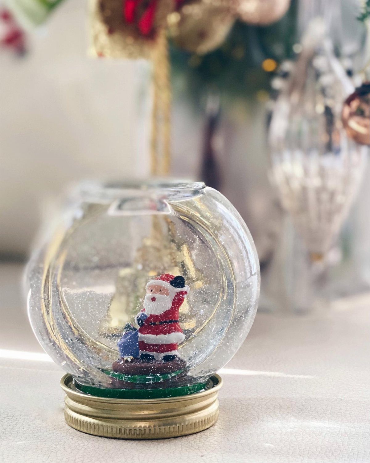Homemade snow globe with a miniature Santa Claus figure inside a glass jar.