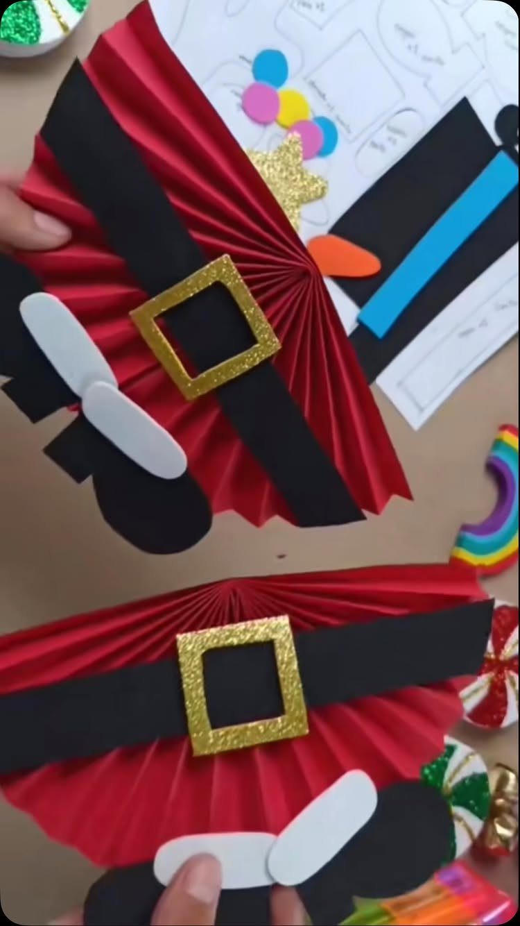 Handmade Santa Claus crafts made from red pleated paper and black paper belts.