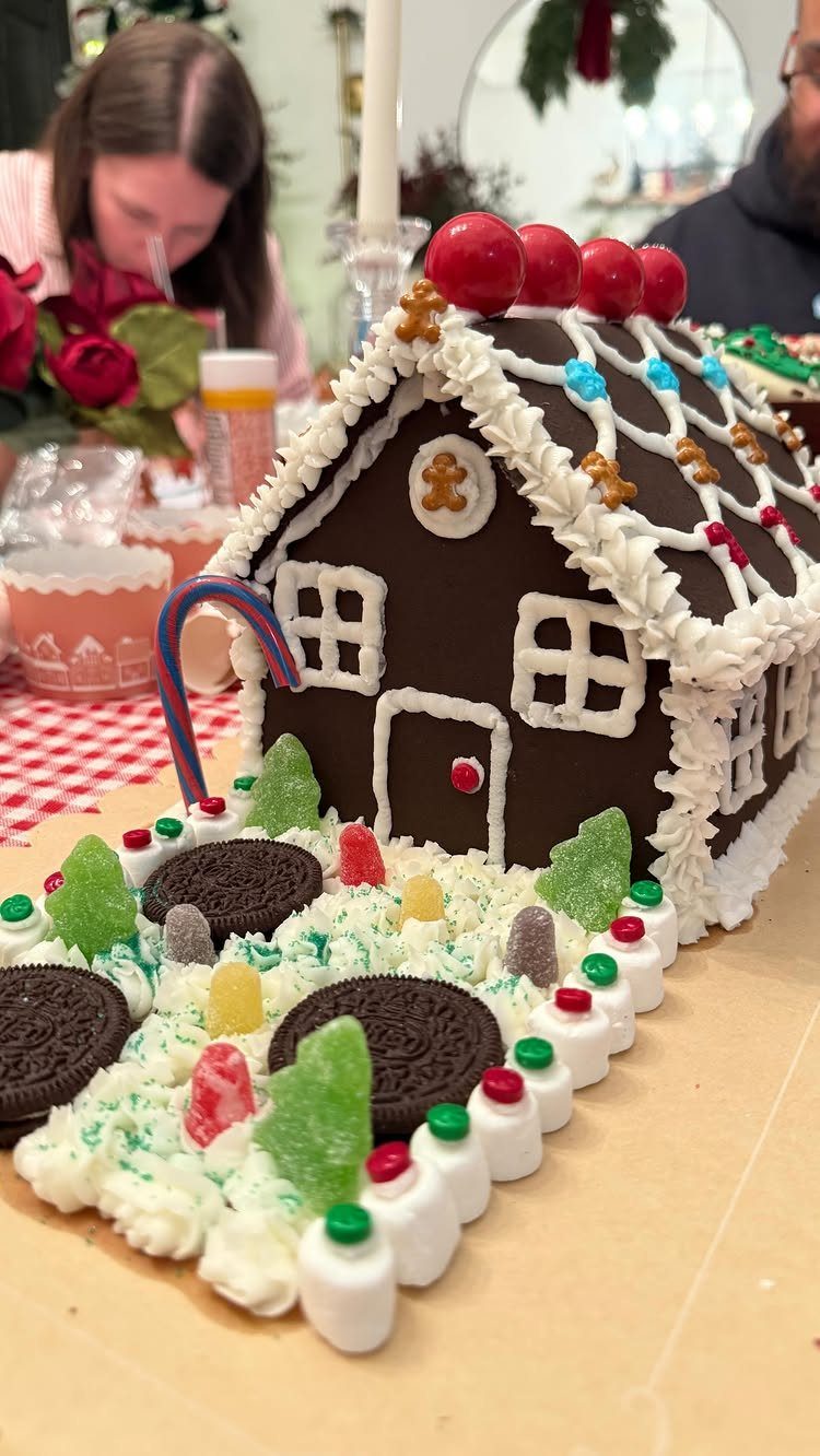 Chocolate gingerbread house decorated with white icing and colorful candies on a table