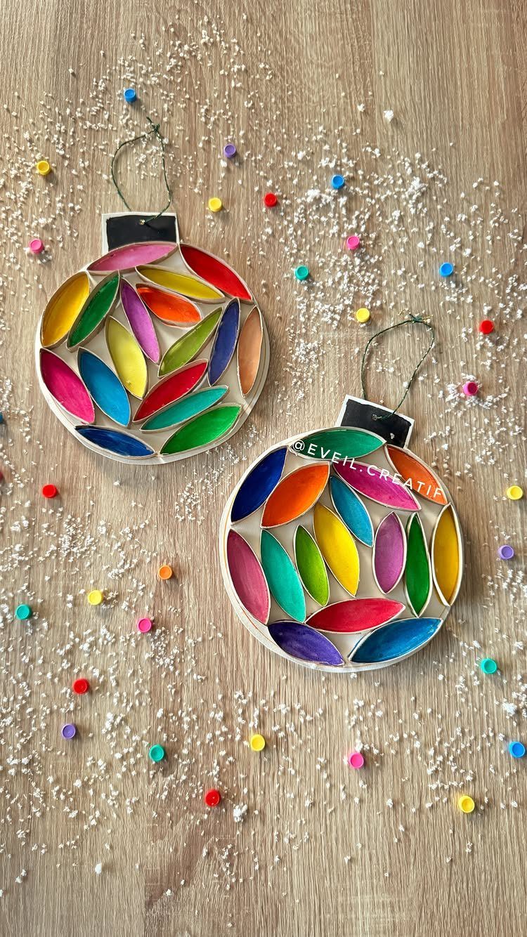 Two colorful handmade circular Christmas ornaments on a snowy wooden surface with beads.