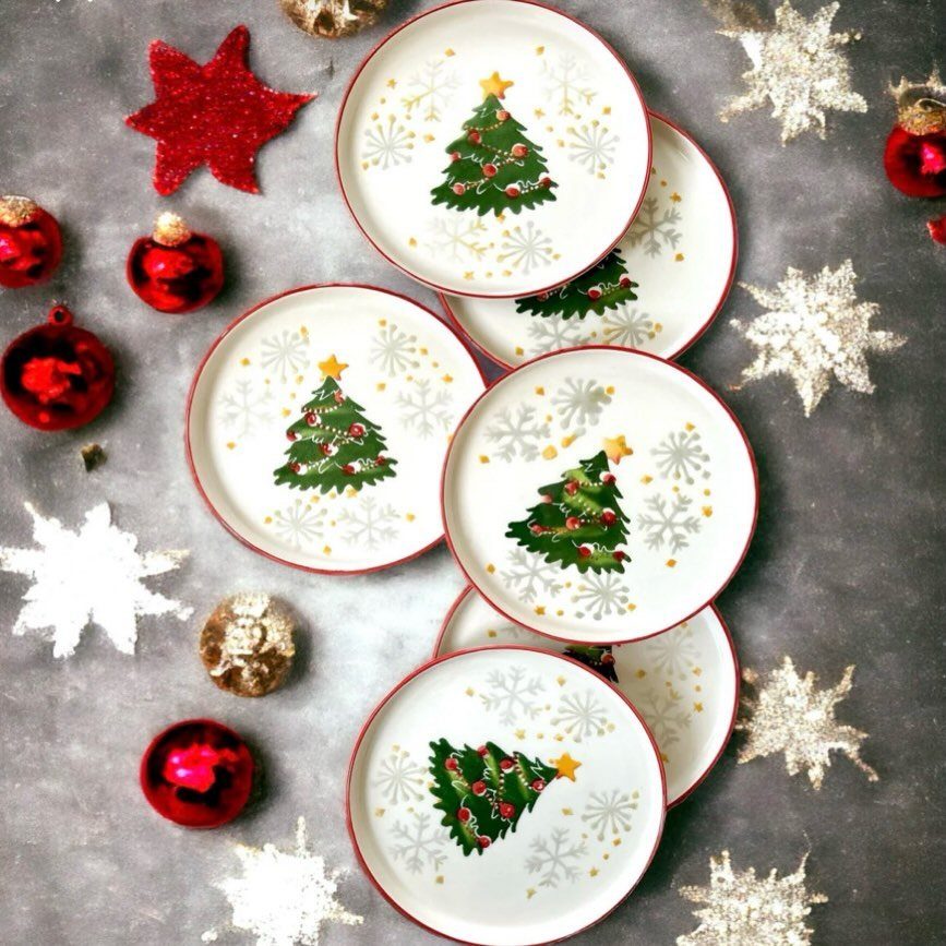 White plates with Christmas tree illustrations surrounded by red ornaments and snowflakes.