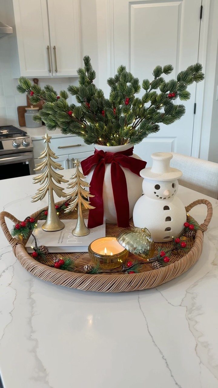 Christmas centerpiece with pine branches, gold trees, and a snowman in a woven tray.
