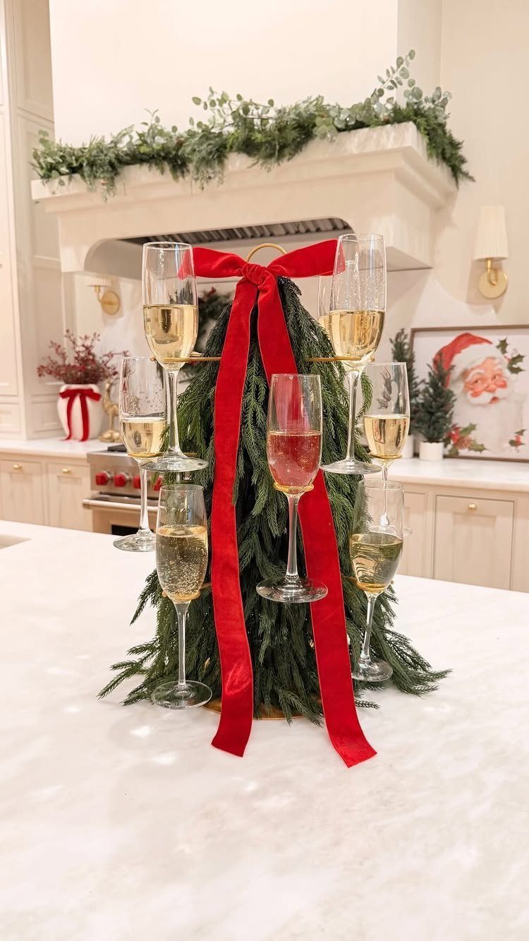Champagne glass tower decorated with pine branches and a red ribbon on marble