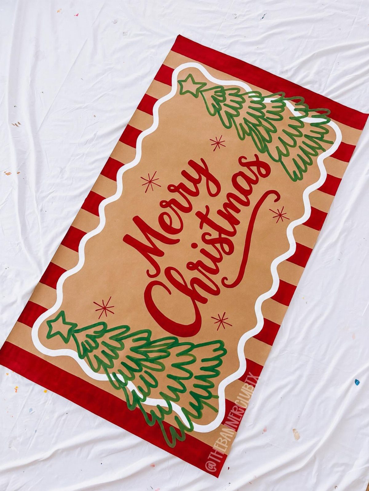 Merry Christmas banner with red stripes and green trees on white fabric