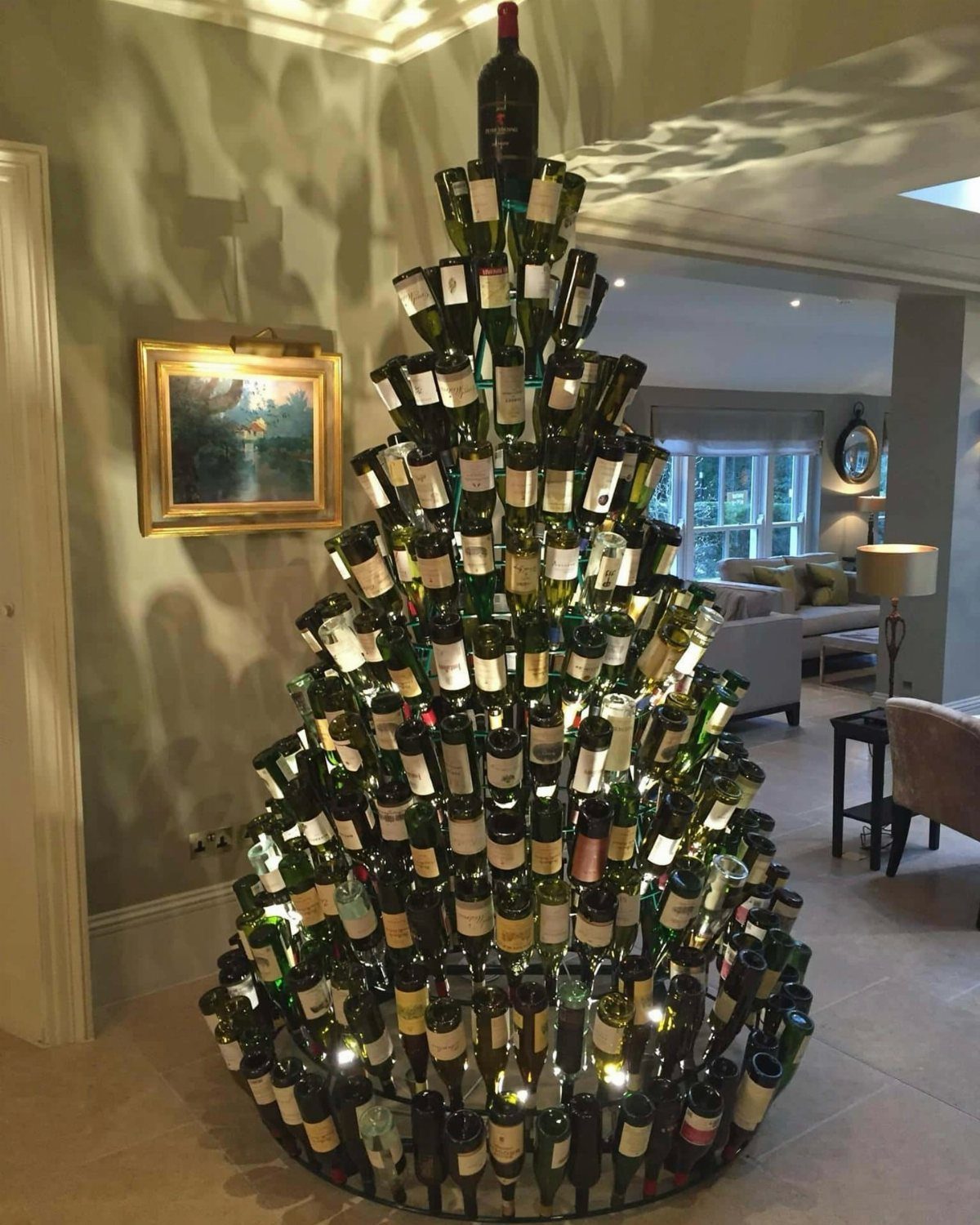 Christmas tree made of green wine bottles lit from within in a living room