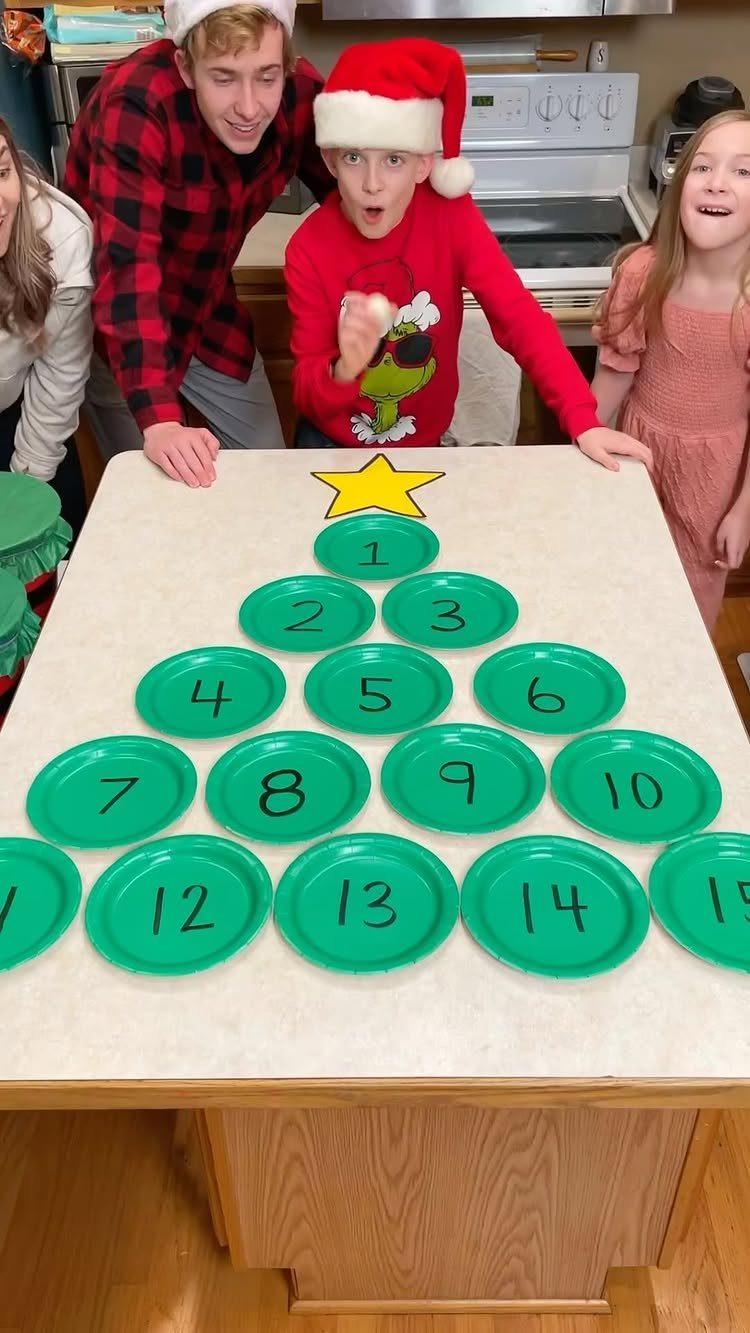People standing behind a Christmas tree shape made of numbered green plates.