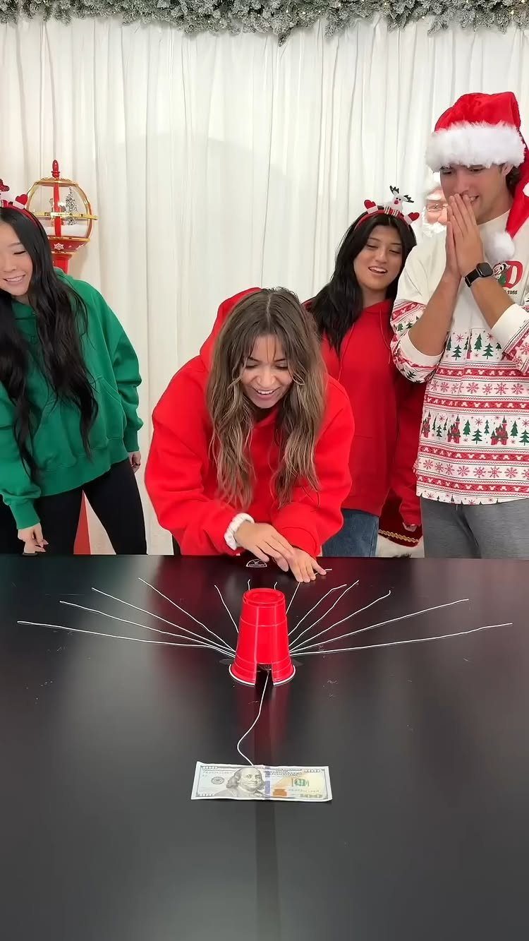 Group of friends playing a cup and string game at a Christmas party