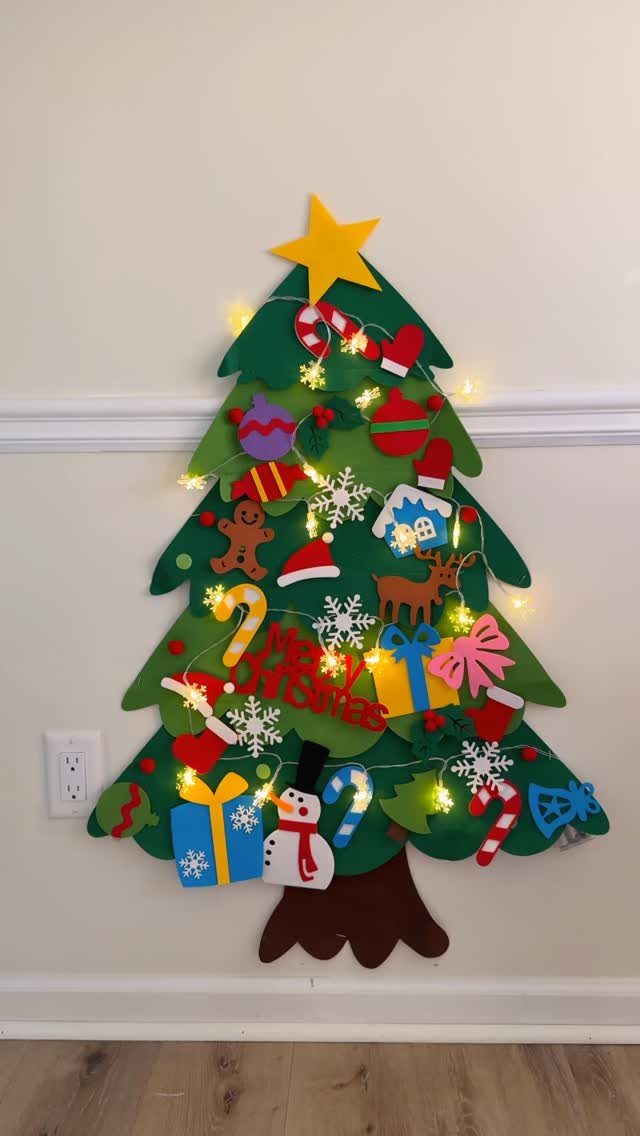Felt Christmas tree on a wall decorated with colorful felt ornaments and fairy lights.