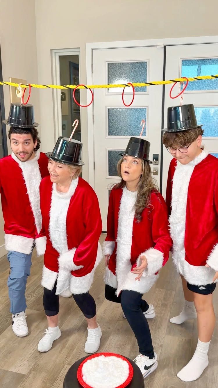 Four people in Santa jackets wearing buckets on their heads for a party game.