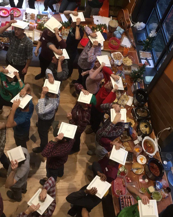 People balancing white plates on their heads during a festive indoor party game.