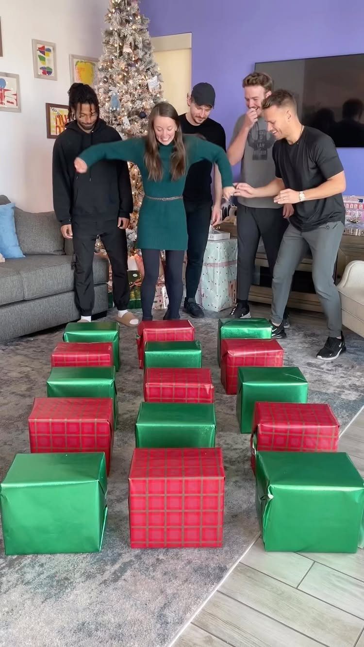 Group of adults playing a game with wrapped gifts in a living room