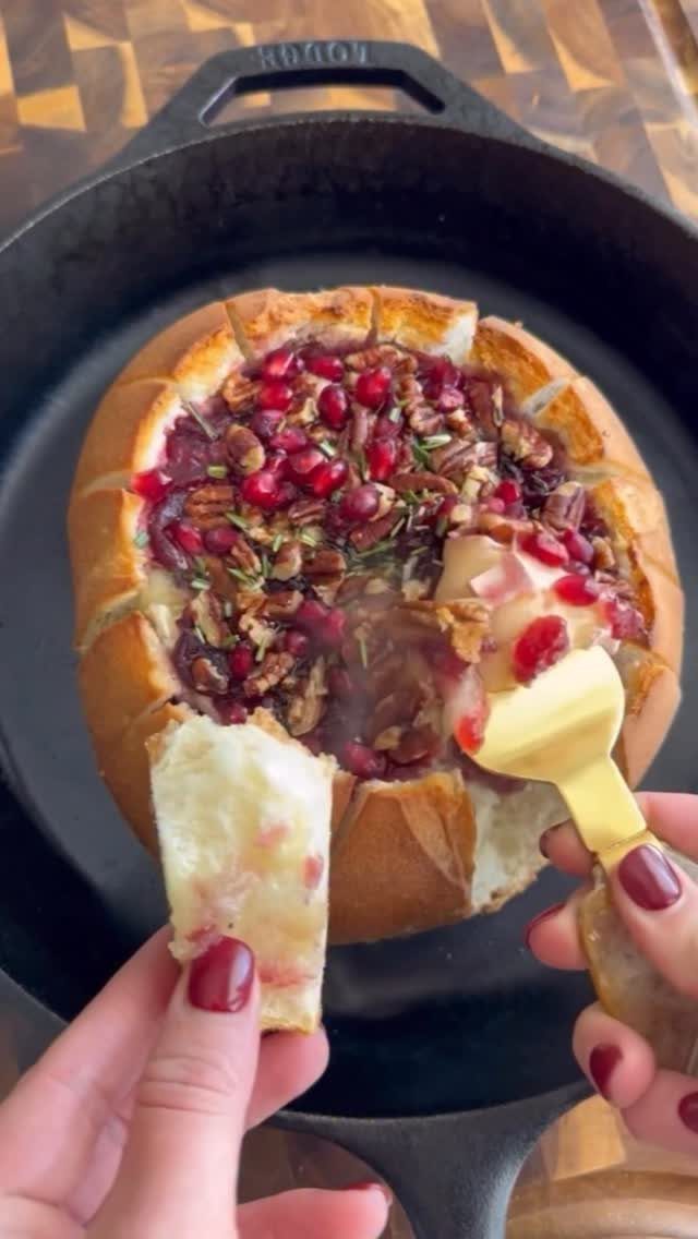 Melted brie with pomegranate seeds and pecans served in a bread bowl skillet.