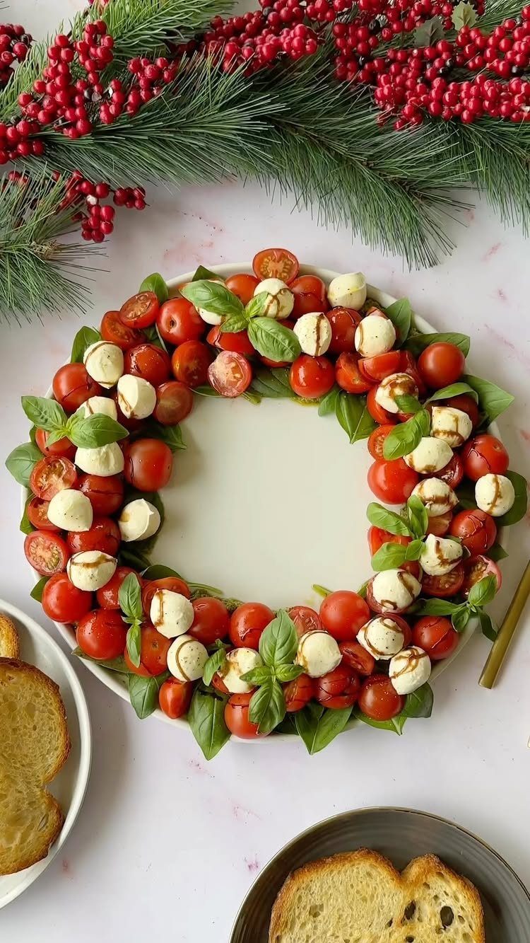 Caprese salad wreath with cherry tomatoes, mozzarella, and basil on a white plate.