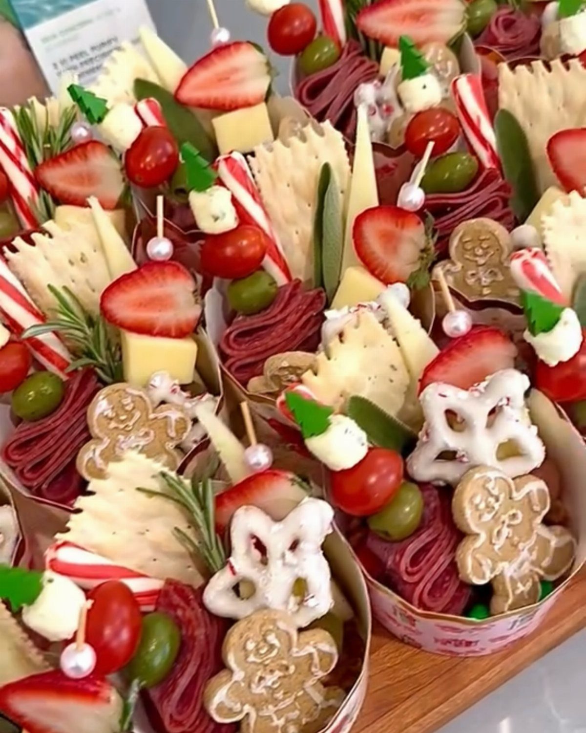 Charcuterie cups filled with meats, cheeses, fruits, and gingerbread cookies for Christmas party.