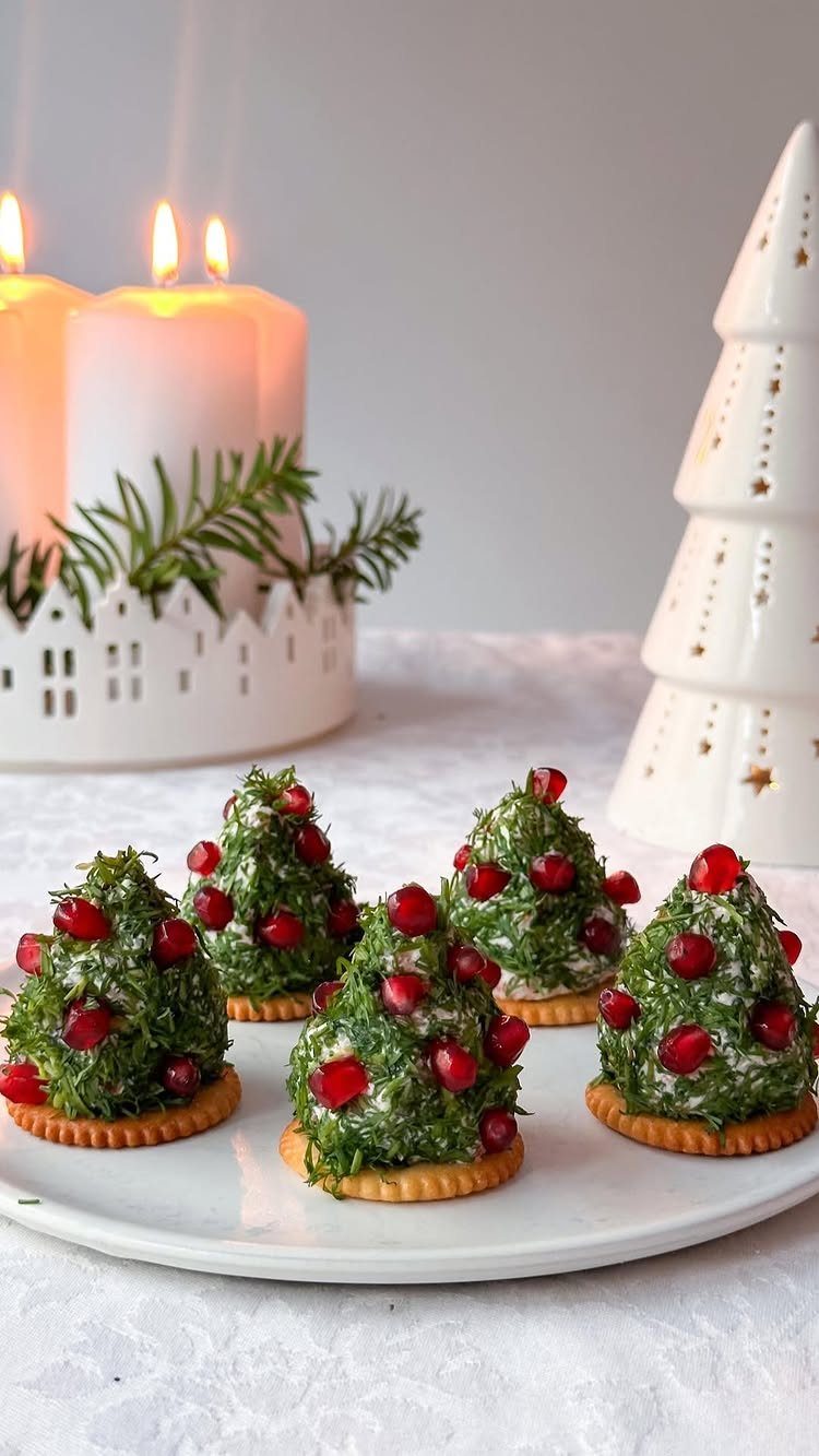 Tree-shaped herb cheese appetizers with pomegranate seeds on crackers on a white plate